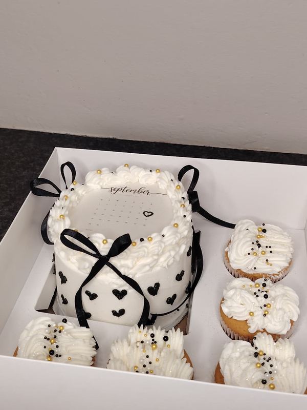 Calendar bento cake with black bows and matching cupcakes in a gift box