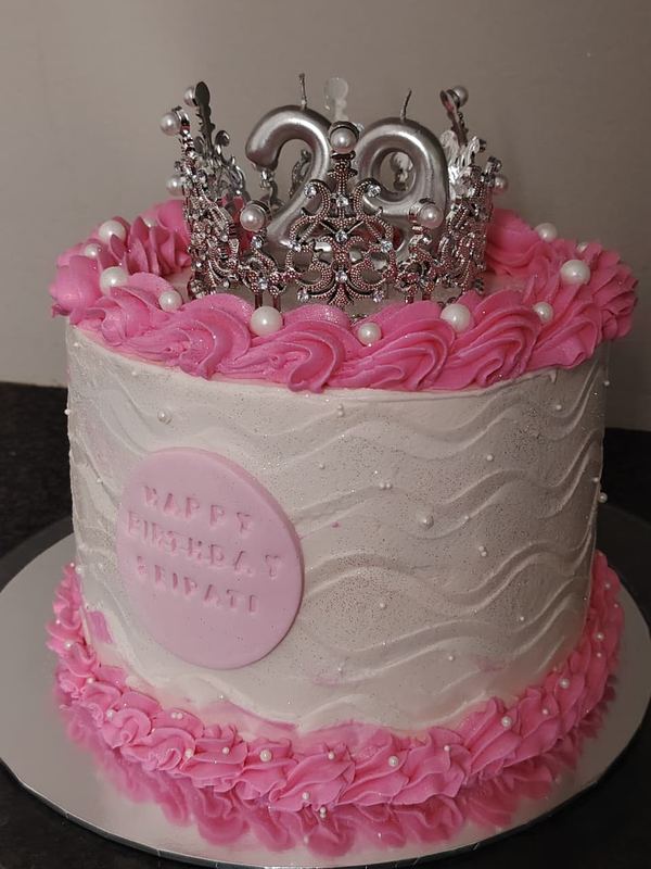 White textured 22nd birthday cake with pink rosettes and a silver crown