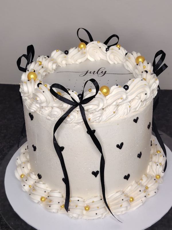 White July calendar cake with black bows and gold pearls
