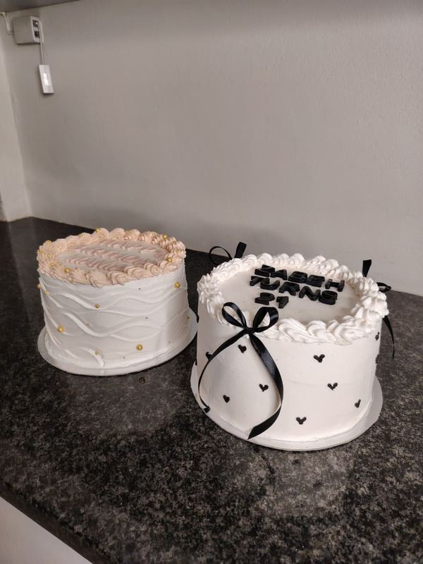 Two celebration cakes with piped borders and black bows