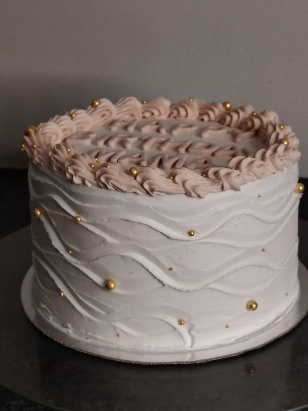 White wave-textured cake with blush rosettes and gold pearls