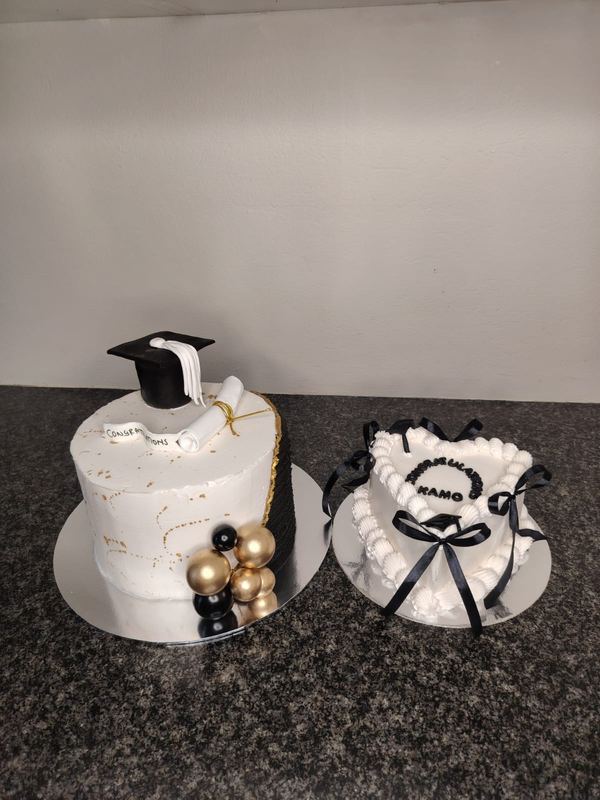 Graduation cake with a mortarboard topper beside a heart cake with black bows