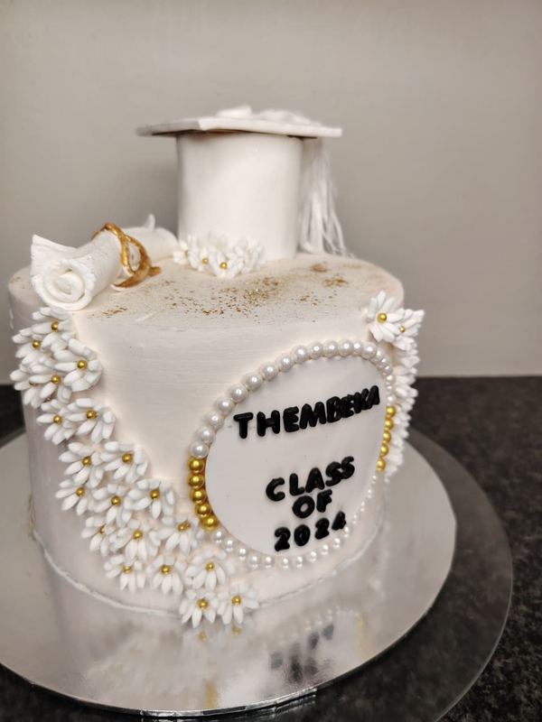 Class of 2024 graduation cake with a mortarboard topper and daisies
