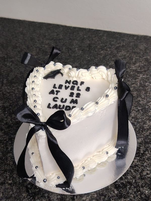 White heart graduation cake celebrating a cum laude pass, with black bows