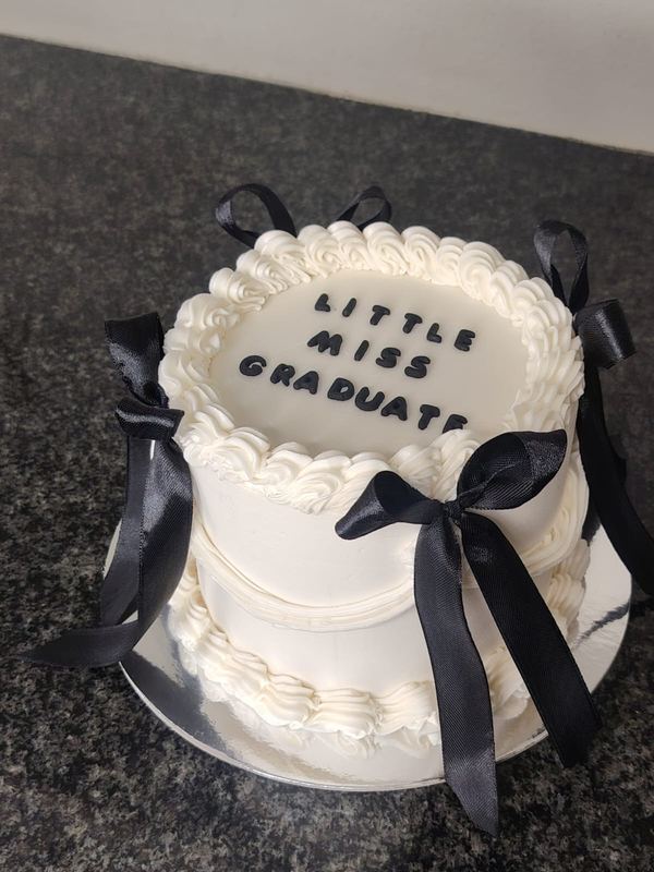 White Little Miss Graduate cake with black ribbon bows