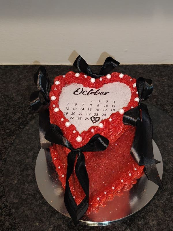 Red heart cake with an October calendar topper and black bows