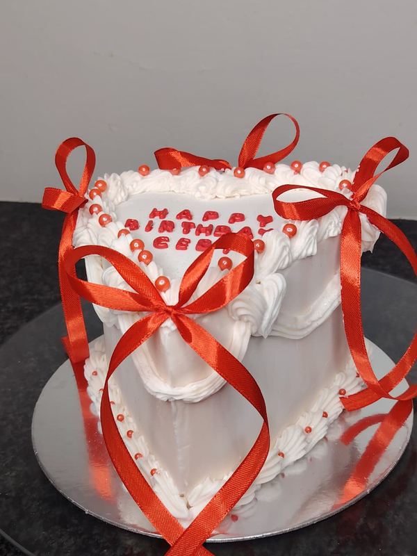 White heart birthday cake with red ribbon bows