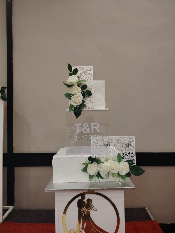 White tiered wedding cake with white roses and a monogram topper